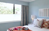 Master bedroom with light blue wallpaper and linen curtains 