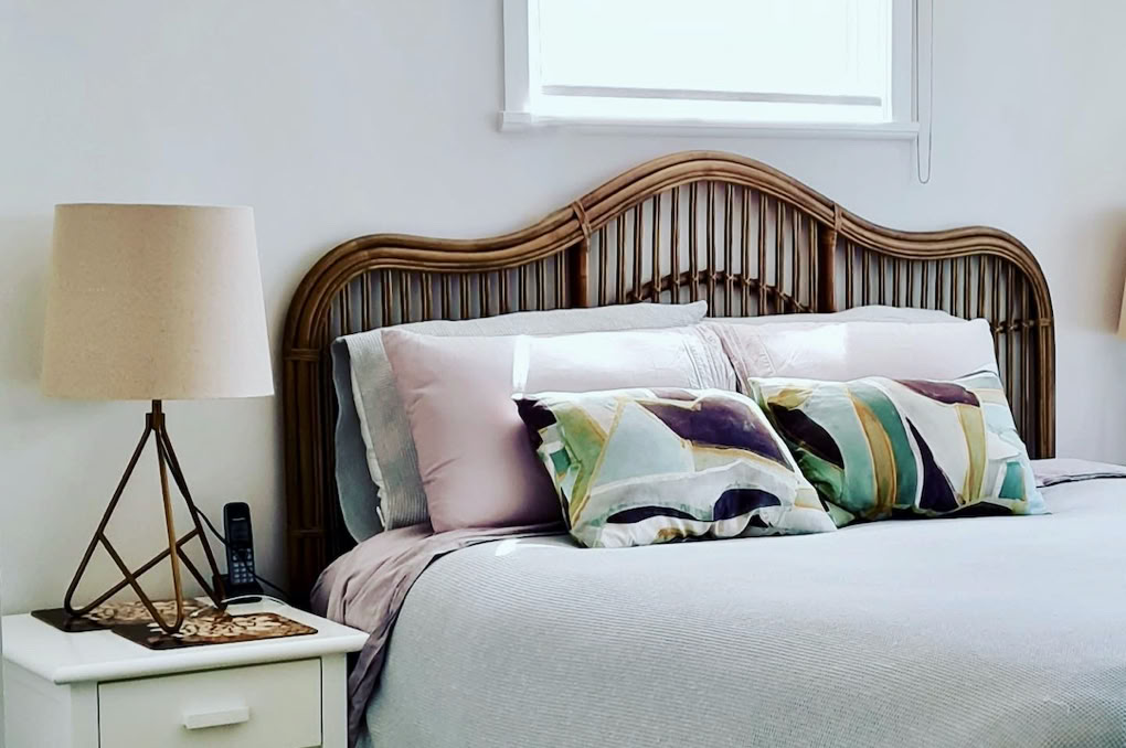 Studio 28 Interio Design Wellington Zealand. Creating wow interiors that are easy on the eye. Bedroom showing ccane bedhaed and beside lamp with decorative pillows.