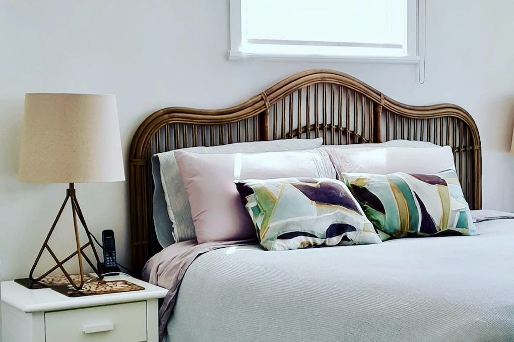 Studio 28 Interio Design Wellington Zealand. Creating wow interiors that are easy on the eye. Bedroom showing ccane bedhaed and beside lamp with decorative pillows.